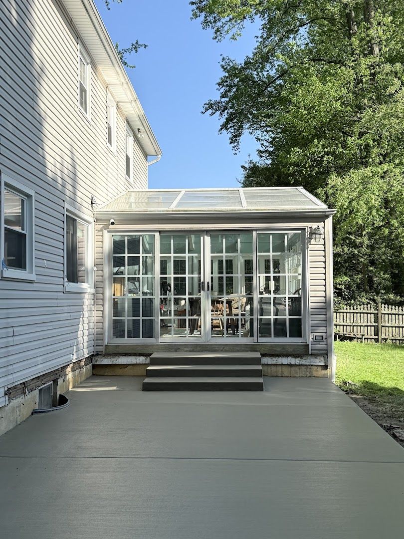 Fresh concrete driveway next to a home sunroom