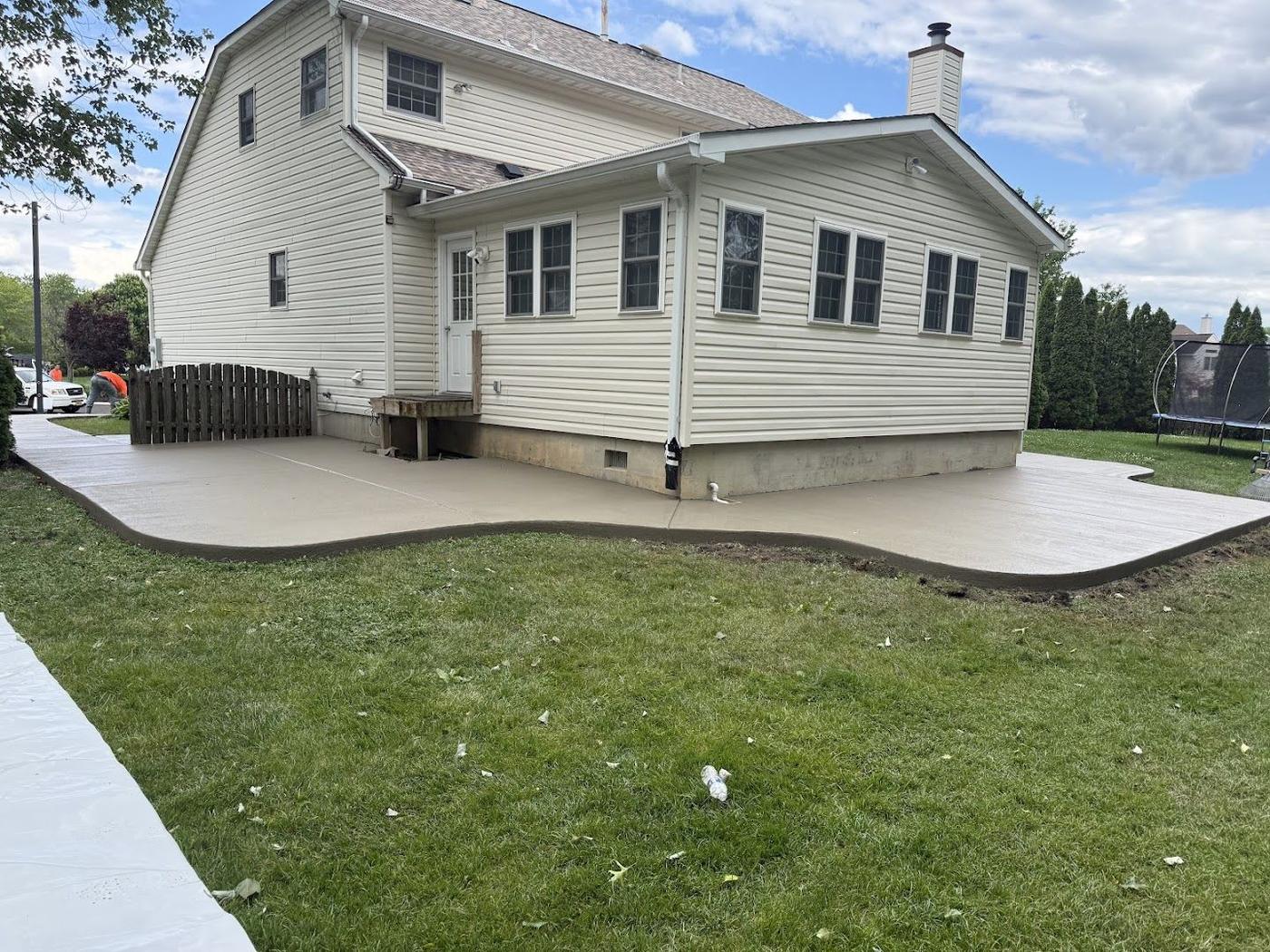 Large finished concrete driveway wrapping a white home